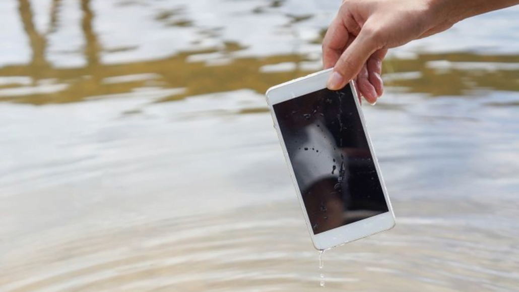 Ilustrasi seseorang sedang mengangkat handphone yang tercebur ke dalam air