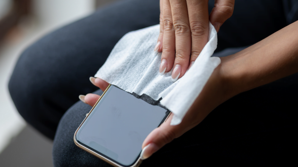 Ilustrasi seseorang sedang mengiringkan handphone nya yang basah menggunakan tisu kering